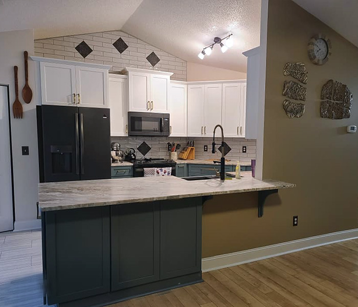 Modern kitchen with white cabinets, black appliances, and updated backsplash design.