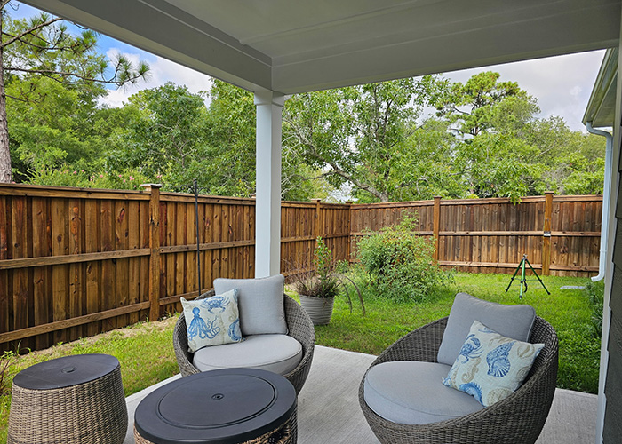 Outdoor covered patio with modern wicker furniture and wood privacy fence.