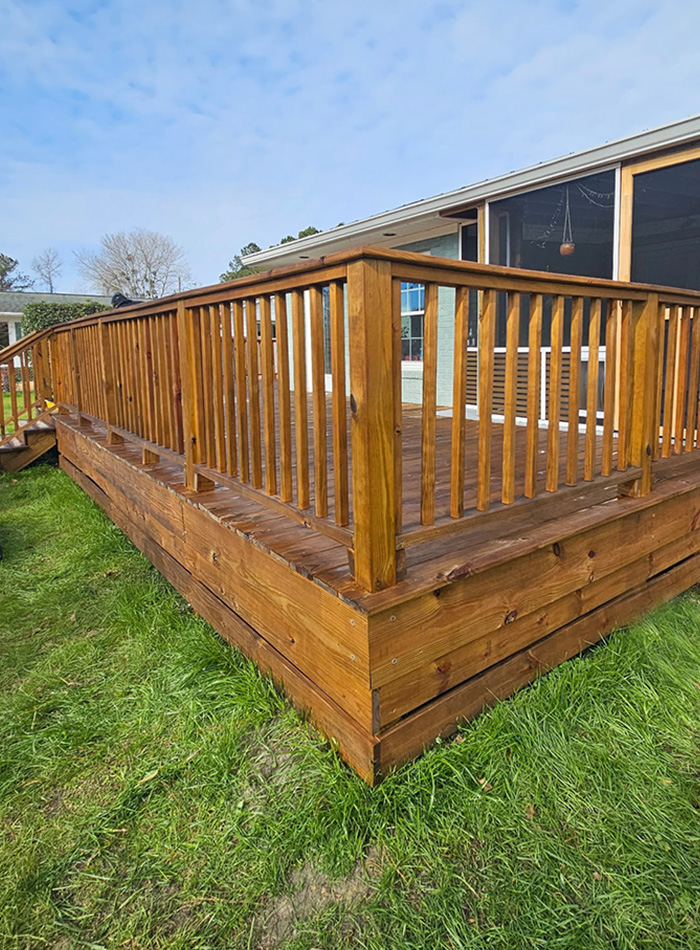 Newly built wooden deck with railing attached to a home exterior.