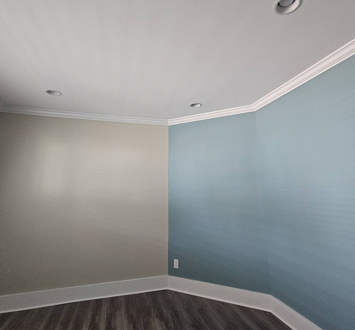 JBG painting project of an empty room with soft blue-gray accent wall and crown molding.