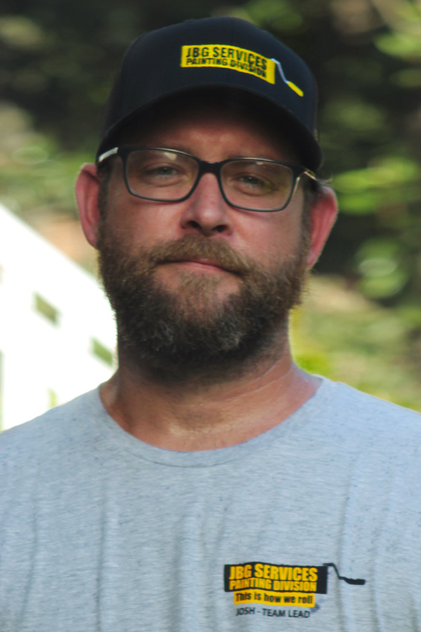 Josh, team lead at JBG Painting, wearing a branded company shirt and hat, representing leadership in professional painting services.