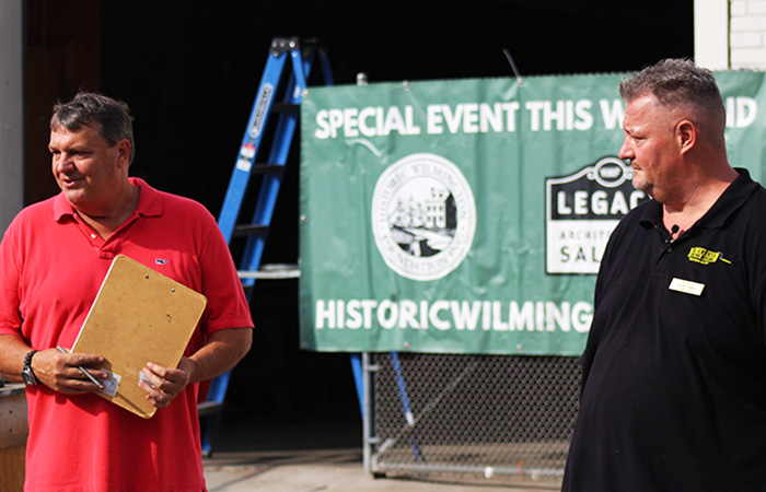 A JBG Painting team member speaks with an event coordinator in front of a Historic Wilmington Foundation banner.