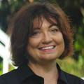Billie, part of the JBG Painting team, smiling outdoors in a professional headshot with a blurred natural background