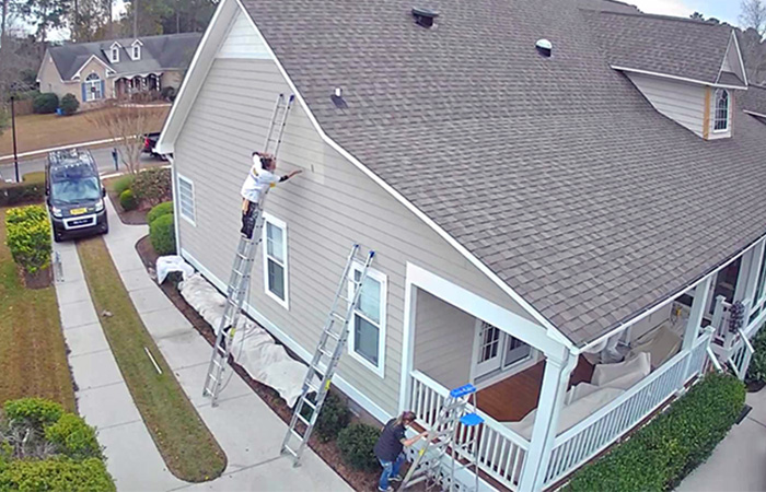 JBG Painting crew using ladders to paint the exterior siding of a beige home in Wilmington, NC.