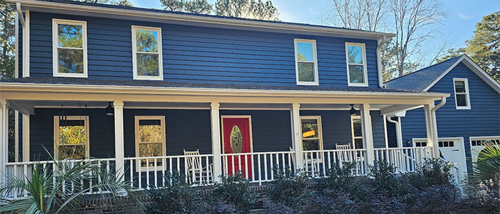 Exterior home painted in deep navy blue with a bold red front door by JBG Painting.