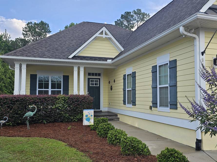 Exterior home painted soft yellow with white trim and blue shutters by JBG Painting for a fresh curb appeal.