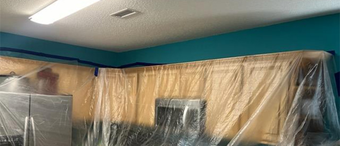 Kitchen cabinets covered with plastic sheeting for interior painting preparation – JBG Painting.