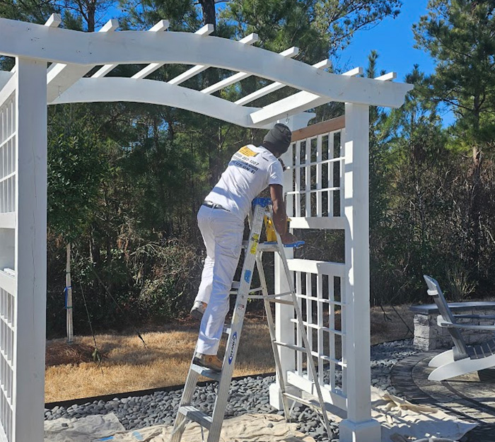 JBG Painting expert painting a white outdoor pergola for a backyard renovation project.