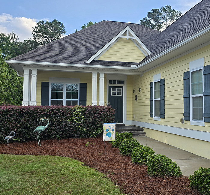Freshly painted yellow house with dark shutters and white trim completed by JBG Painting exterior services.